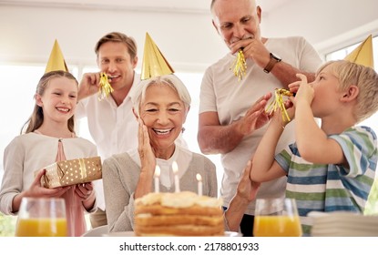 Senior woman celebrating her birthday with family at home, wearing party hats and blowing whistles. Grandma looking at birthday cake and looking joyful while surrounded by her grandkids and and son - Powered by Shutterstock