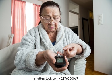 Senior Woman Checking Blood Sugar Level Using Home Glucometer. Old Person With Diabetes At Home In Living Room.. Diabetes Treatment For Elderly People. 