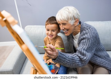 Senior woman with child painting on canvas. Grandmother spending happy time with grandson. Small boy listening to his grandmother who is teaching him to paint on canvas at home. - Powered by Shutterstock