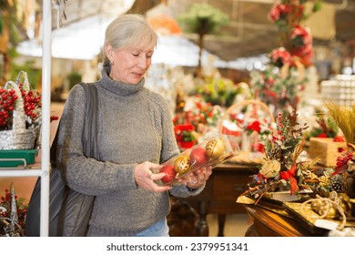 Senior woman choosing christmas decorations in home goods store.