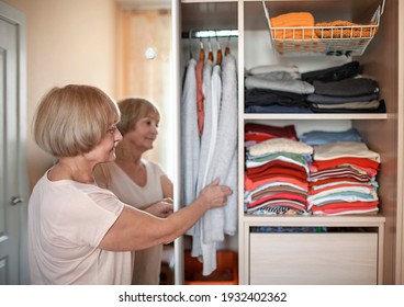 Senior woman choosing outfit from wardrobe closet with clothes and home stuff. Cleaning, organizing and order in the closet - Powered by Shutterstock