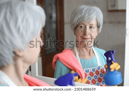 Senior woman cleaning a mirror 