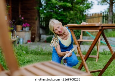 Senior Woman Cleaning And Renovating Garden Furniture And Getting The Garden Ready For Summer