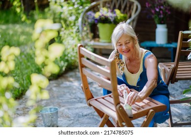 Senior woman cleaning and renovating garden furniture and getting the garden ready for summer - Powered by Shutterstock