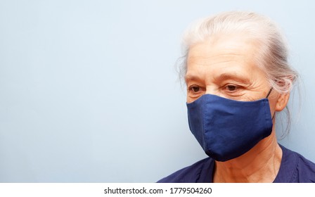 Senior Woman In A Cloth Mask Is Not Looking At The Camera On A Blue Background. Banner