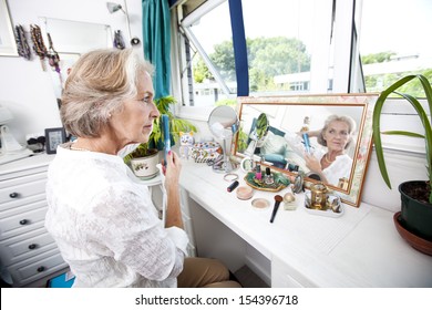 Senior Woman Combing Her Hair At Dresser In House