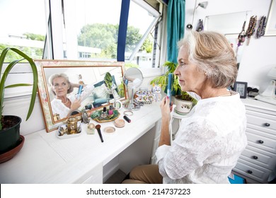 Senior Woman Combing Her Hair At Dresser In House