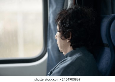 A senior woman in contemplation by a train's window, scenery passing by - Powered by Shutterstock