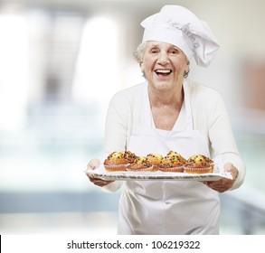 senior woman cook holding a tray with muffins, indoor - Powered by Shutterstock