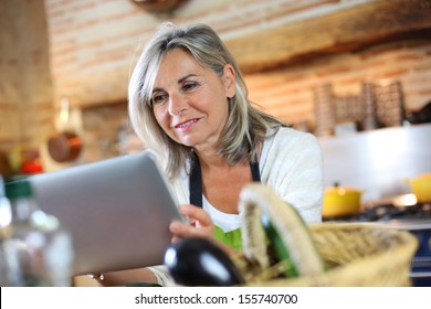 Senior Woman Cooking With Help Of Recipe On Tablet