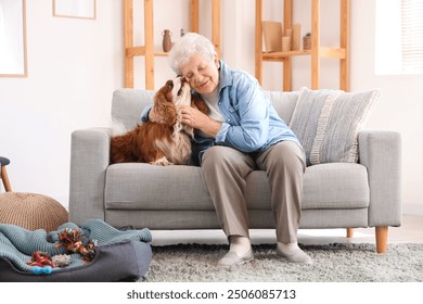 Senior woman with cute cavalier King Charles spaniel dog sitting on sofa at home - Powered by Shutterstock