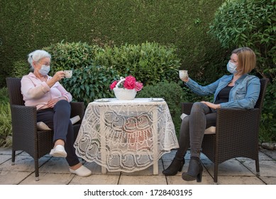 Senior woman and daughter having coffee at safety distance in the garden, - Powered by Shutterstock