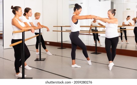 Senior Woman Demonstraiting Ballet Moves With One Of Her Students During Group Dance Training.