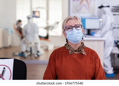 Senior Woman In Dental Clinic Wearing Face Mask Looking At Camera Wainting For Consultation During Global Pandemic With Coronavirus. Concept Of New Normal Dentist Visit In Covid-19. Outbreak.