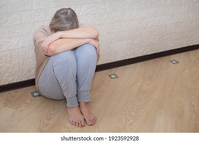 Senior Woman With Depression Stress Sad Sitting On The Floor. The Concept Of Sadness, Loneliness, Old Age. The Concept Of Psychological Health, Emotional Anxiety, Panic Attack, Menopause, Migraine.