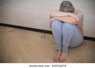 Senior Woman With Depression Stress Sad Sitting On The Floor. The Concept Of Psychological Health, Emotional Anxiety, Panic Attack, Menopause, Migraine. The Concept Of Sadness, Loneliness, Old Age.