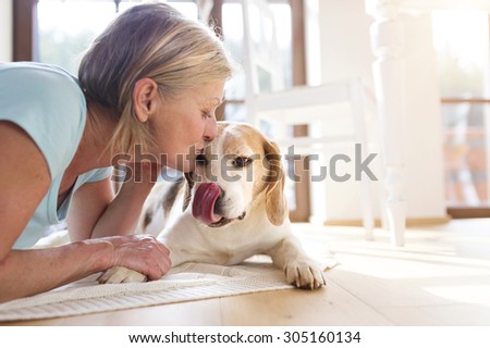 Senior woman with dog inside of her house. 