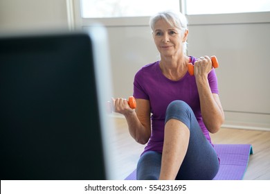 Senior Woman Doing Fitness Exercices In Front Of Tv