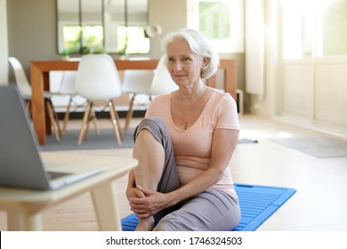 Senior Woman Doing Fitness Exercises At Home Through Virtual Class