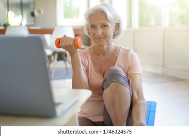 Senior woman doing fitness exercises at home through virtual class - Powered by Shutterstock