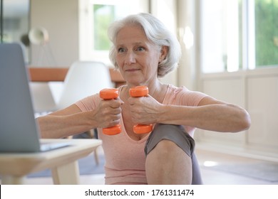 Senior Woman Doing Fitness Exercises With Virtual Class, Holding Dumbbells