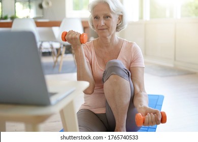 Senior Woman Doing Fitness Exercises At Home Through Virtual Class