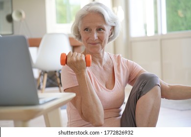 Senior Woman Doing Fitness Exercises With Virtual Class, Holding Dumbbells