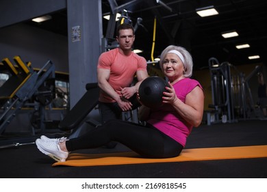 Senior Woman Doing Situps With Medicine Ball, Working Out With Personal Trainer