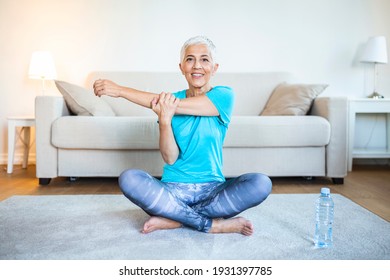 Senior Woman Doing Warmup Workout At Home. Fitness Woman Doing Stretch Exercise Stretching Her Arms - Tricep And Shoulders Stretch . Elderly Woman Living An Active Lifestyle.