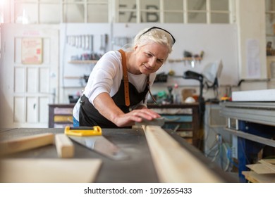 Senior woman doing woodwork in a workshop - Powered by Shutterstock