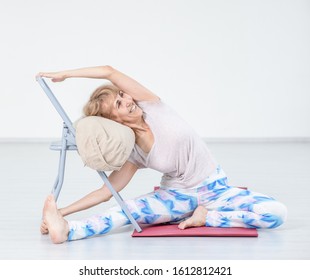 Senior woman doing yoga with chair at home. Stretching exercises