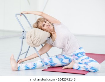 Senior Woman Doing Yoga With Chair At Home. Stretching Exercises