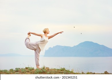Senior woman doing yoga exercises with mountain on the background