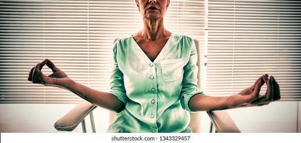 Senior Woman Doing Yoga On Chair At Fitness Studio