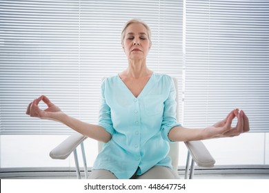 Senior Woman Doing Yoga On Chair At Fitness Studio