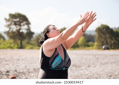 Senior woman with dreadlocks in stretching position by the sea at morning. Elderly woman doing yoga near beach. - Powered by Shutterstock