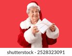 Senior woman dressed as Santa Claus with letters on red background