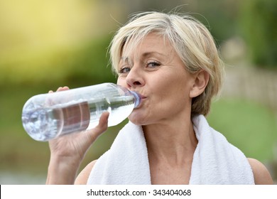 Senior woman drinking water after exercising - Powered by Shutterstock