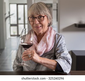 Senior Woman Drinking Wine At A Table.