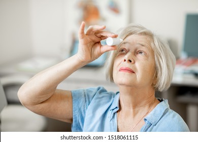 Senior Woman Dripping Some Medicine With Dropper On Her Eyes At The Ophthalmological Office. Concept Of Eye Treatment With Eye Drops