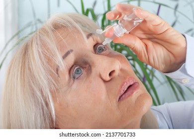 Senior Woman Drips Eye Drops Into Her Eyes. Woman Suffering From Irritated Eyes Or Eye Diseases. Vision And Ophthalmology Medicine.