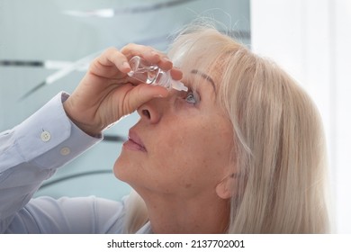 Senior Woman Drips Eye Drops Into Her Eyes. Woman Suffering From Irritated Eyes Or Eye Diseases. Vision And Ophthalmology Medicine.