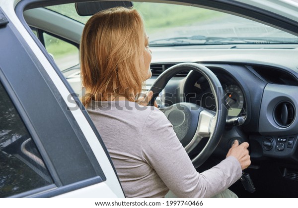 Senior woman driver starts her car with a key, is
about to leave