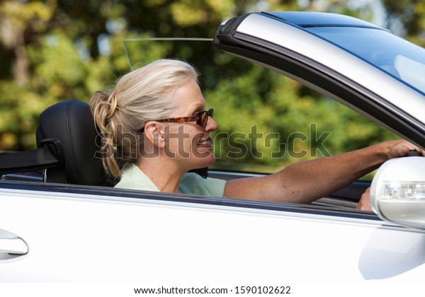 A senior woman driving a\
car