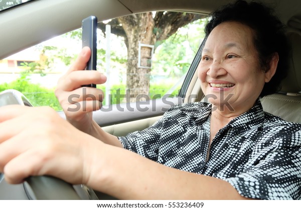 Senior woman driving car
and cellphone