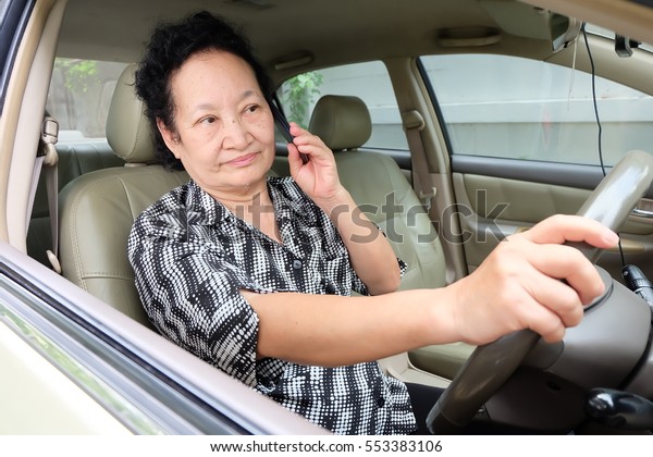 Senior woman driving car
and cellphone