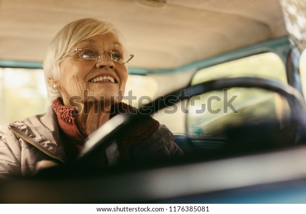 Senior\
woman driving car on winter day concentrating on the road. Elderly\
female wearing glasses driving a car\
carefully.
