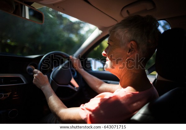 Senior woman driving car\
on sunny day