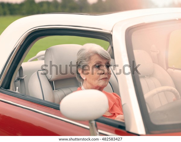 Senior woman driving red\
convertible