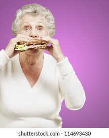 Senior Woman Eating A Healthy Sandwich Against A Pink Background